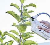 Porometer leaf clip with dark shields measuring stomatal conductance on a green plant leaf in natural light