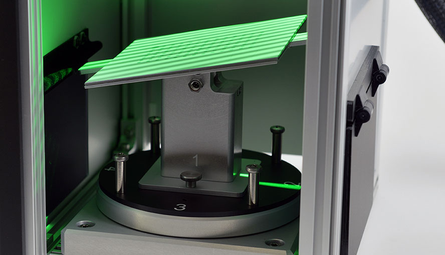 Tilted calibration plane illuminated by a stripe pattern of green light.